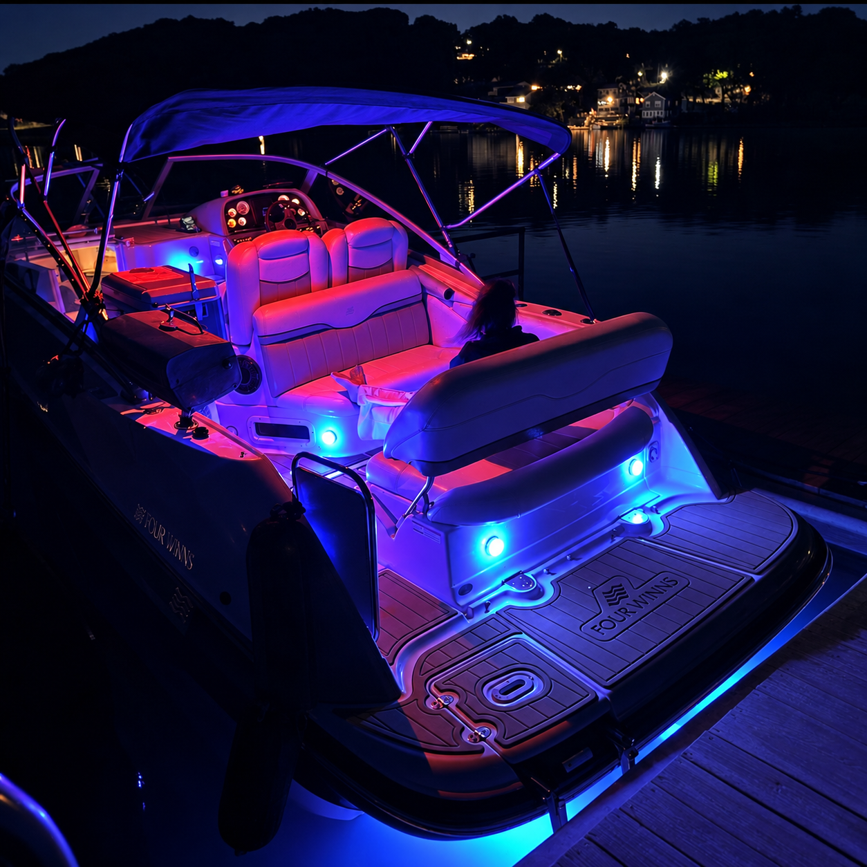 Cockpit do Four Winns Vista 258 à noite, iluminação colorida e luzes subaquáticas azuis na água